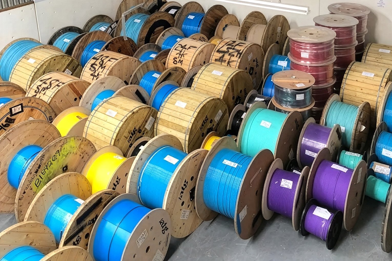 Different-coloured fibre optic cable drums in an industrial setting.