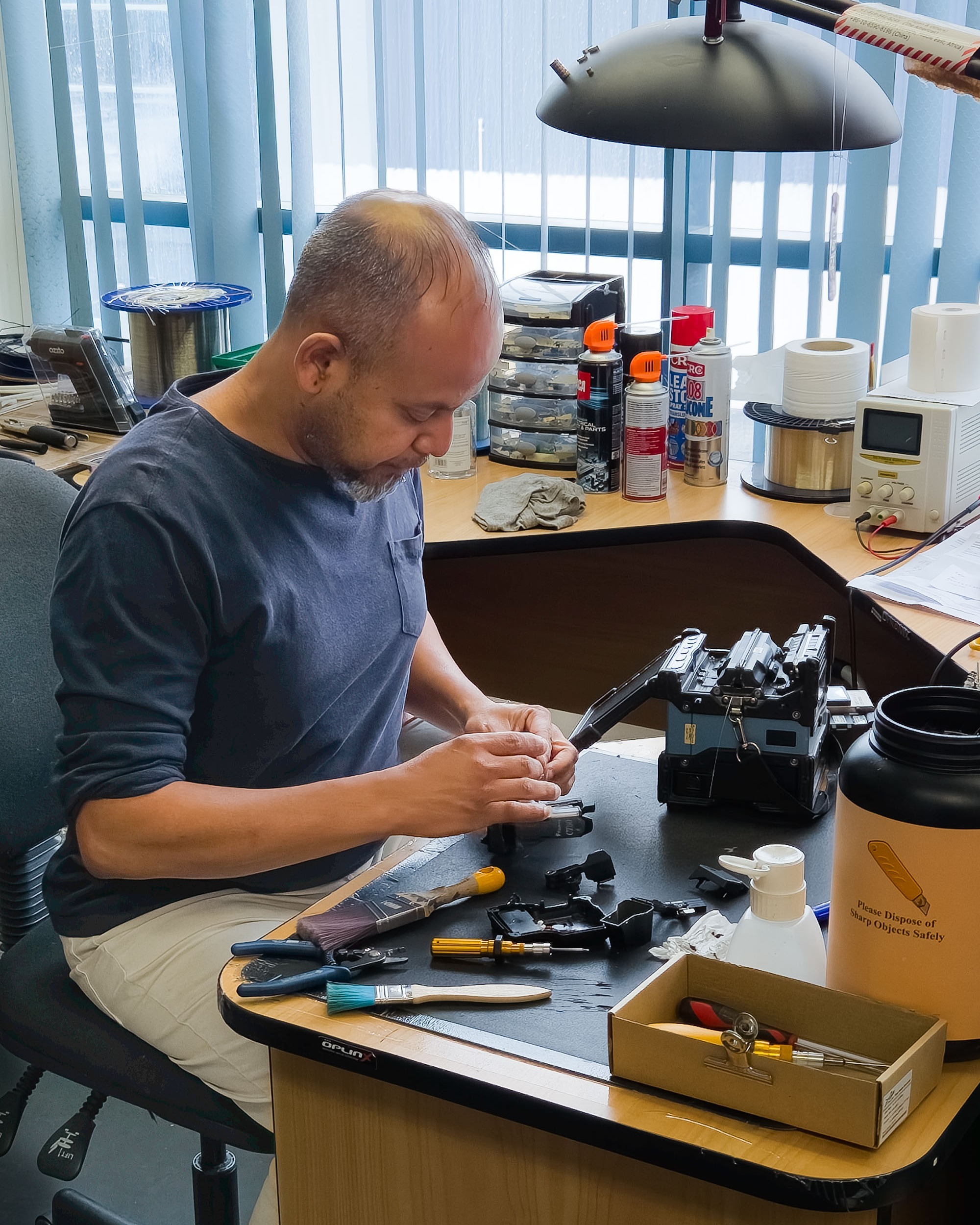 Person servicing a fibre optic splicing machine in an office.