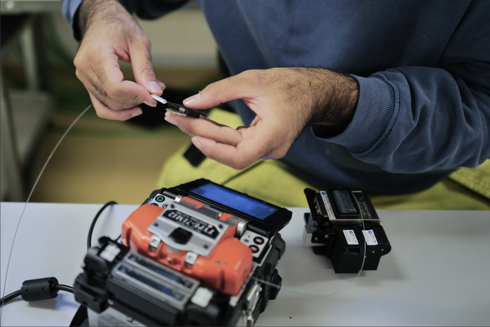 Close-up of a fibre technician splicing a fibres with a splicing machine.