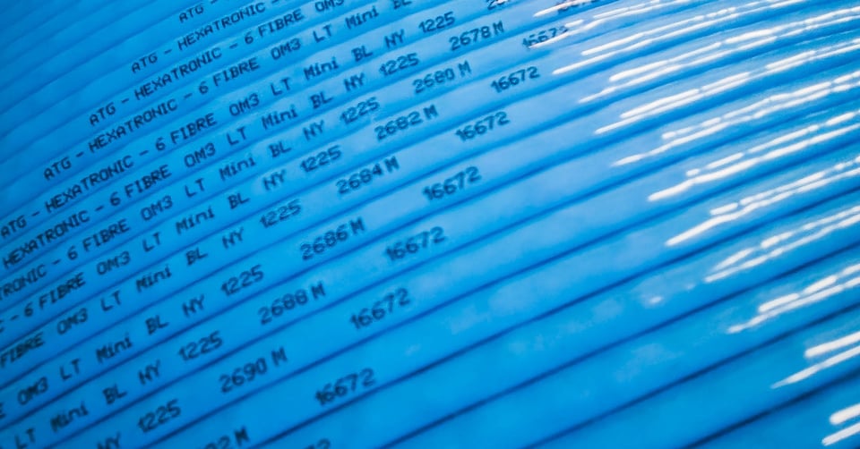 Close-up of a bright blue fibre optic cable labelled atg and Hexatronic.