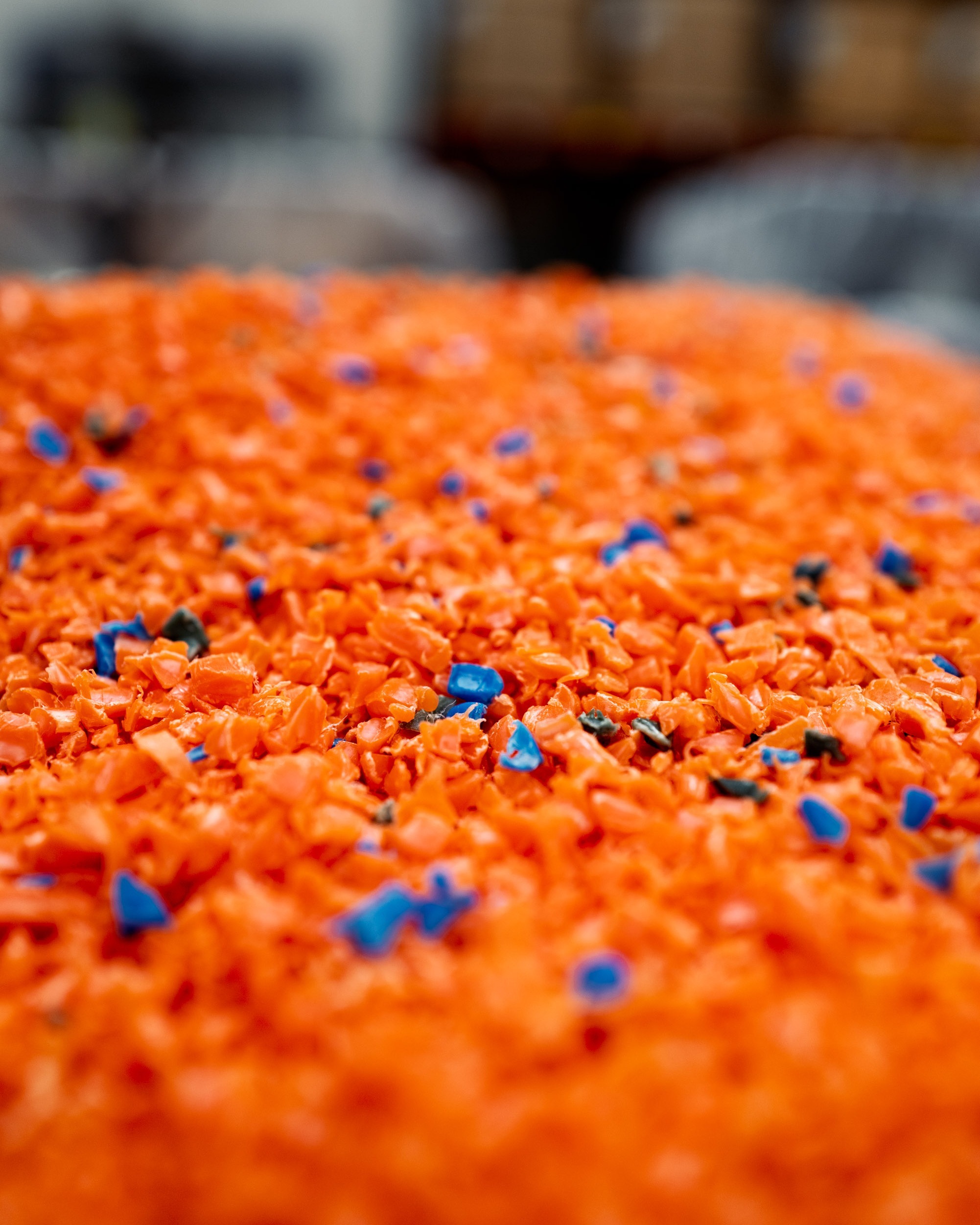 Pile of orange plastic granules mixed with blue and black pieces.