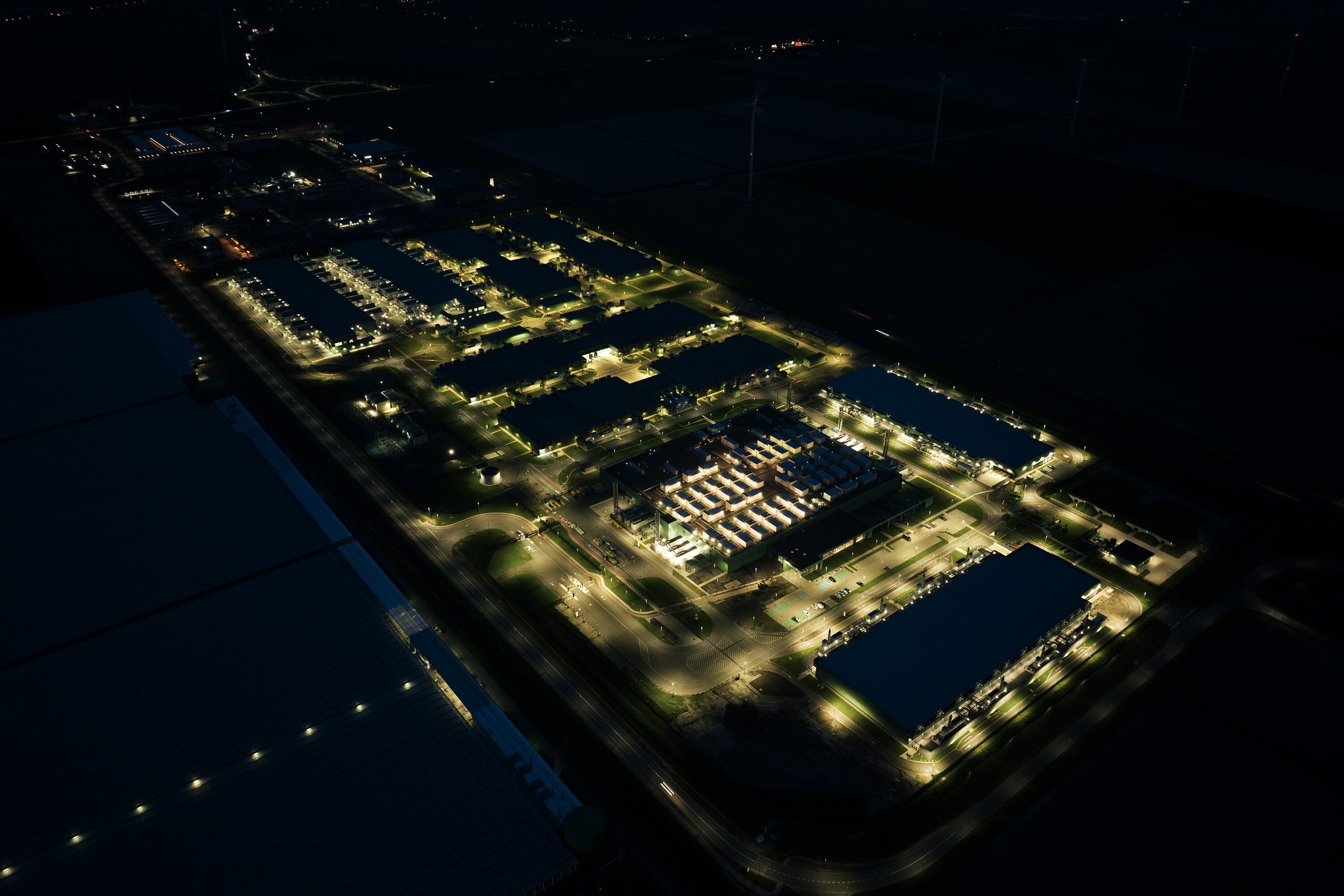 Aerial view of a lit-up data centre at night. 